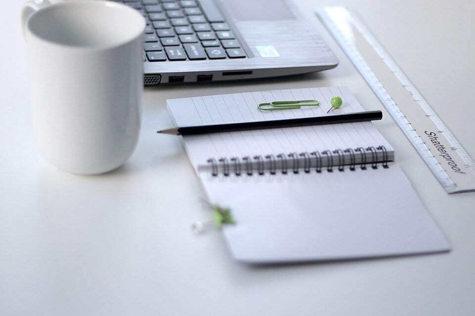 Laptop, notebook, mug, and ruler on a clean office desk
